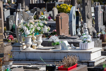 Stèle et pierre tombale d'un enfant dans un cimetière de ville. La tombe est recouverte de fleurs...