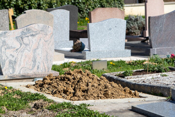 Tombe en cours de préparation dans un cimetière de ville. Aménagement d'une sépulture, la terre...