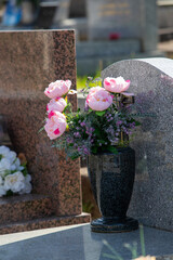 Le fleurissement d’une tombe avec un bouquet de fleurs rose. Cela permet de rendre hommage au défunt et de témoigner son attachement et le respect envers cet être cher.