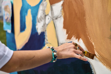 Female adult hand brings vibrant mural to life, showcasing creativity with brush strokes. Bright...