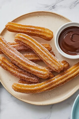 Golden churros coated in sugar served on a plate with rich chocolate dipping sauce, captured from above in a clean, appetizing presentation.