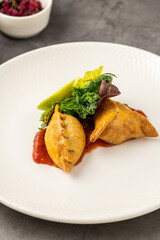 Meat empanadas on tomato sauce, served with fresh greens and lime wedge