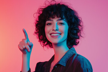 Woman with curly hair smiling and pointing upward against a pink and blue gradient background.