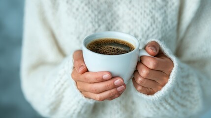 A pair of hands gently holding a warm cup of coffee, adorned with a cozy knitted sweater, evoking feelings of warmth, comfort, and the simple pleasures in life during chilly days.