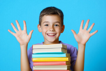 A smiling young boy with short brown hair holds a stack of colorful books in front of him, raising both hands against a bright blue background.