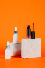 Mockup of black blank thin tube - mascara, lip gloss, gel, eyeliner, oil, etc. Cosmetic package with stylish props on orange background.