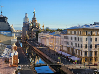 City street with a river Griboyedov running through it. There are many people walking along the...