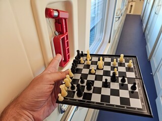 Man is holding a chess board with a red and white piece emergency brake. The board has a black and...