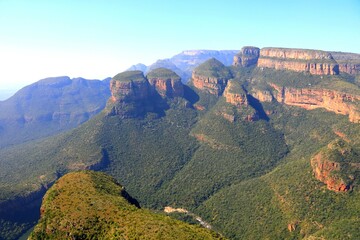 Aerial view of Three Rondavels in Blyde River Canyon, South Africa. Iconic red rock formations and dense green valley.