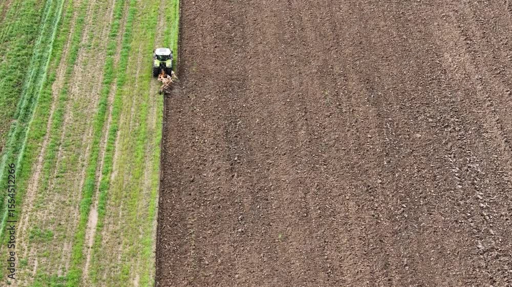 Poster aerial view of a farmer plowing the field with a tractor and preparing the land for sowing, creating