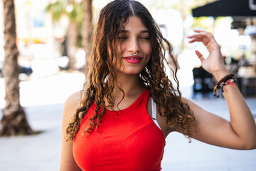 Young woman touching curly hair while walking down the street