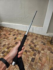 Person is holding a black and silver object. The object is a stick with a metal tip for safety...