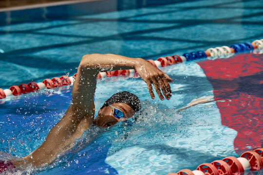 Male swimmer in action above French flag at the bottom of a pool. Focus on performance, identity, and international sportsmanship. Concept of international swimming events
