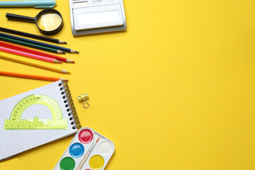 Children school supplies flat lay on yellow background with copy space