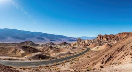 Fototapeta premium Vast Desert Landscape with Winding Road and Distant Mountains Under a Clear Blue Sky