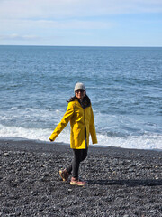 Strolling on Reynisfjara Beach in vibrant yellow amidst Icelands stunning coastal beauty