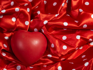 concept of love, passion. Red heart arranged on a red satin background with white polka dots. Saint Valentine, Valentine's Day