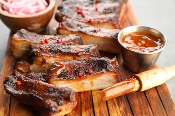 Delicious pork ribs, sauce and brush on grey table, closeup