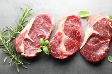 Pieces of raw beef meat and spices on grey table, flat lay
