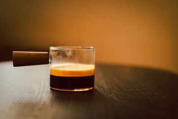 Espresso coffee in a glass cup on wooden table.