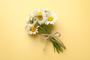 Bouquet of chamomile flowers on yellow background, top view