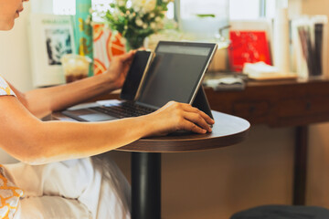 Woman hand holding computer mouse working on laptopin cafe.
