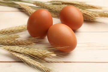 Fresh eggs and spikes on light wooden table, closeup