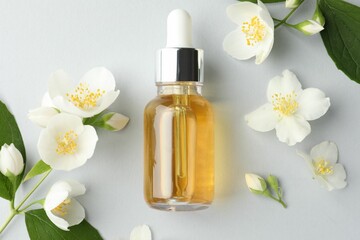 Cosmetic product and jasmine flowers on light background, flat lay
