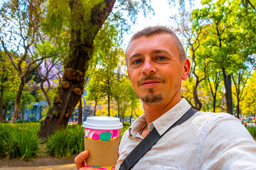 Handsome man drinks coffee to go in a park Mexico.