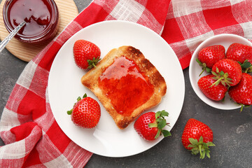 Toast with tasty homemade strawberry jam and berries on grey table, flat lay