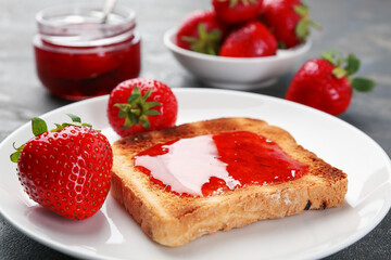 Toast with tasty homemade strawberry jam and berries on grey table, closeup