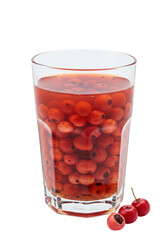 A glass full of red berries suspended in liquid with three berries laying near