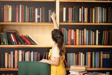 Cute little girl choosing a book for reading in a home library © zulfiska