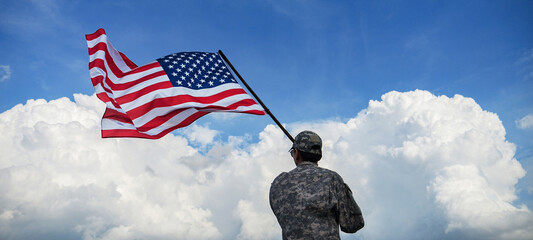 back side of soldier in military uniforms is standing waving a America flag under blue sky in celebration of the nation holiday for 4th of July, Memorial Day, Independence Day and celebrate victory
