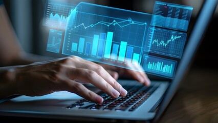Hands typing on laptop with futuristic holographic financial data charts and graphs