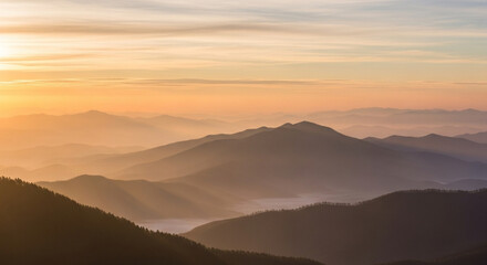 Obraz premium A cinematic aerial view of a serene sunrise over misty mountains. Layers of hills fading into the horizon with gentle clouds floating, creating a peaceful and natural atmosphere.