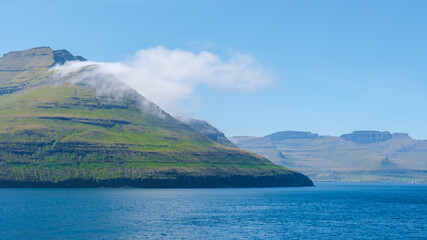 Breathtaking coastal view of the Faroe Islands with lush green hills and serene blue waters