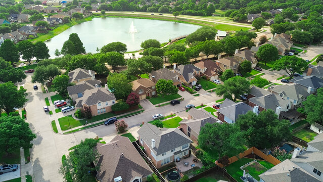 Rheudasil Park in Flower Mound, Texas, featuring pond with fountain, boardwalk, walking trails, lush green trees, playground, and surrounding suburban homes in the Dallas Fort Worth metroplex