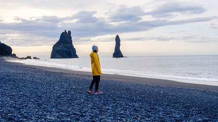 Waves caress Reynisfjara Beach as a solitary figure enjoys the dramatic Icelandic coastline