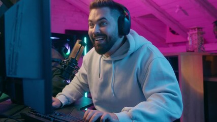 Excited winner champion Caucasian guy male gamer streamer man winning luck achievement victory internet win talking microphone play online game addict in headphones gaming streaming in neon dark room
