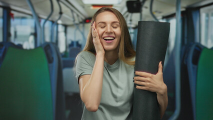 Woman carrying yoga mat smiling inside bus suggests active lifestyle and travel routine merging...