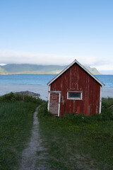Rustic red cabin by the tranquil shore of Norway offers scenic coastal views and serene ambiance