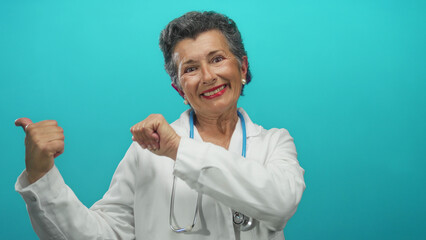 Senior grey-haired female doctor with a stethoscope smiles confidently against a bright blue...