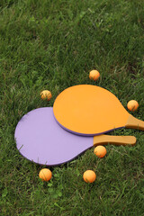 Beach tennis rackets and ball on grass. Beach tennis set. Bright wooden rackets for outdoor games....