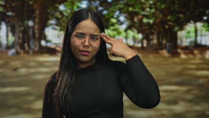 Woman holding hand in a gun gesture in a park setting with hispanic and latin style for a young...