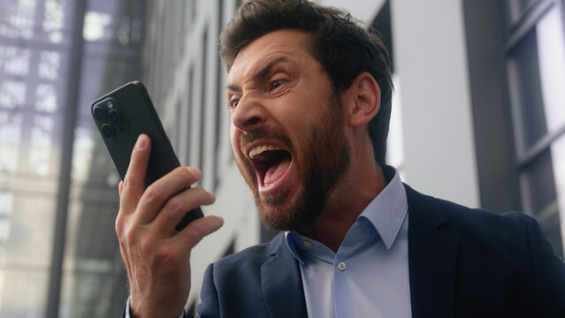 Fototapeta Furious aggressive crazy mad stressed authority anger screaming scolding yelling adult Caucasian businessman employer business man middle-aged male talking mobile phone arguing conflict guy in city