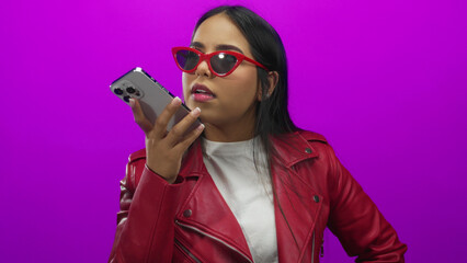 Woman leans over phone while sending voice note in an isolated room to showcase her young latin...