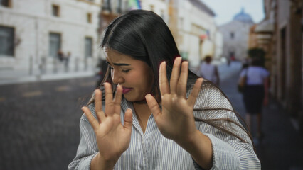 Young woman expressing emotion in a historic old town street during daytime with blurred buildings...
