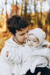 Happy father hugging and kissing cute baby son in soft evening light in autumn woods. Fatherhood....