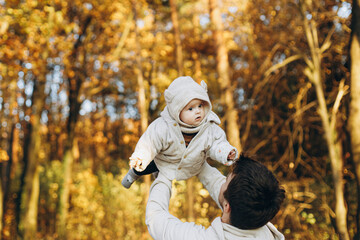 Happy father playing with cute baby son in soft evening light in autumn woods. Fatherhood. Stylish...